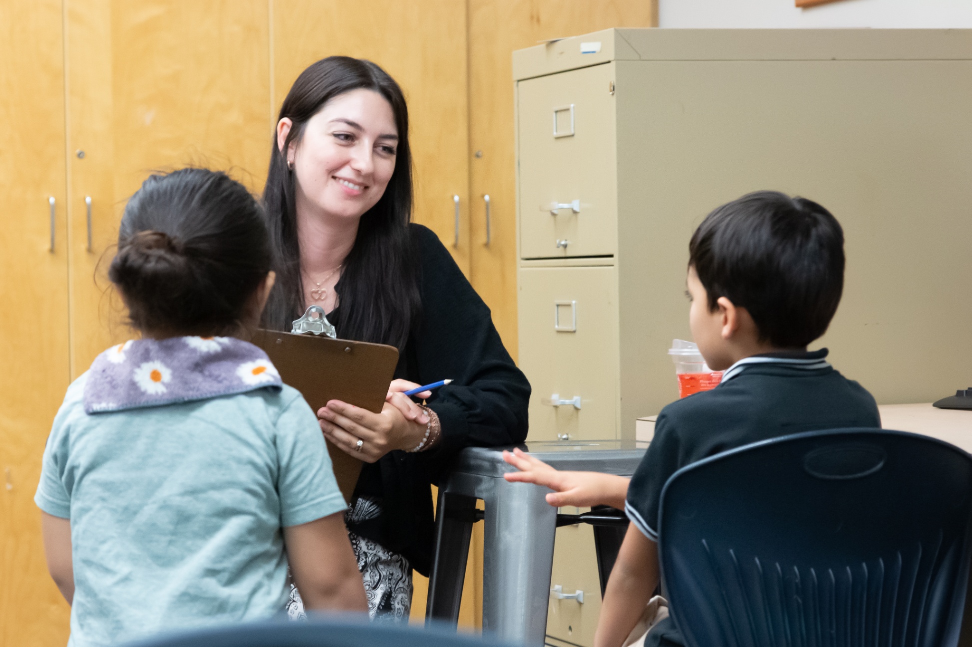 A teacher assessing the English language skills of two young learners
